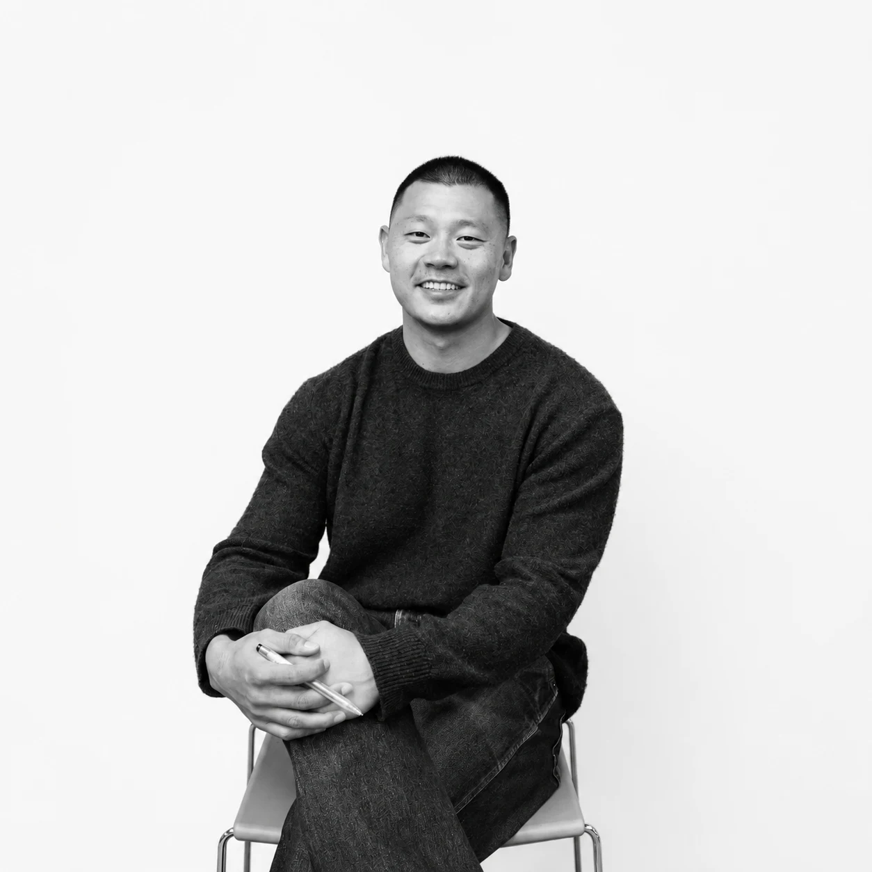 Black-and-white portrait of Joel Chan seated against a plain studio background.